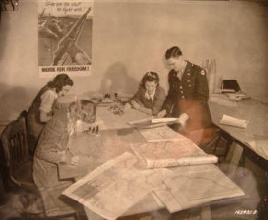 A black and white photo of personnel working around a map table (Courtesy of NGA).